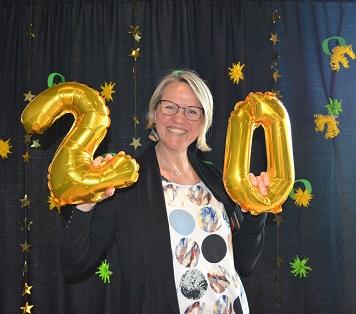 Employee holding balloons that make the number 20